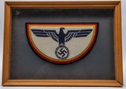 A Third Reich decorative panel of woven eagle and swastika overlaid on subsequent yellow, red and