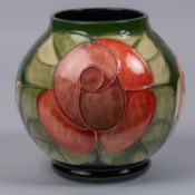 A Moorcroft pottery globular vase. With stylised floral design on a green base. Marks etc to base