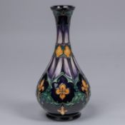 A Moorcroft pottery vase. With fleurs-de-lys and acanthus leaf design on dark purple ground. Marks