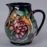 A large Moorcroft pottery jug from 2008. With multi-colour foral design on a purple ground. Marks