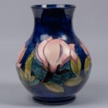 A Moorcroft pottery vase. With magnolia design on a dark blue ground. Marks and sticker to base,