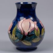 A Moorcroft pottery vase. With magnolia design on a dark blue ground. Marks and sticker to base,