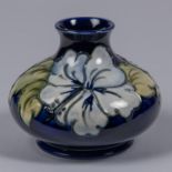 A Moorcroft pottery vase. Earlier floral design by Walter Moorcroft on a dark blue ground. Impressed