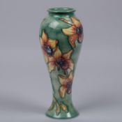 A Moorcroft pottery tall vase. With iris type flowers on green ground. Marks to base, MP, HC date