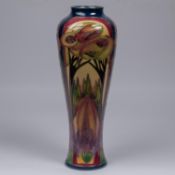 A Moorcroft pottery tall vase. A scene with trees in muted Art Nouveau colours by Rachel Bishop.