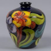 A Moorcroft pottery vase. With lilies on dark blue ground. Marks to base, DJS, racquet date cypher