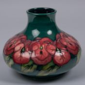 A Moorcroft pottery vase. Purple flowers on a green ground. Marks to base, TRIAL, CS and flag date