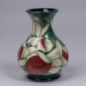 A Moorcroft pottery vase. Stylised white flowers with red stemen on a green ground. Marks to base,