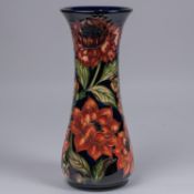 A Moorcroft pottery vase. With orange flowers on dark blue ground. Marks to base, SP, jug date