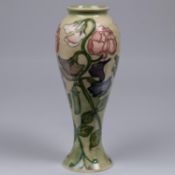 A Moorcroft pottery tall vase. With sweet peas on a light graded green base. Impressed marks to