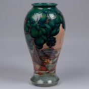 A Moorcroft pottery tall vase. With stylised trees and landscape. Impressed marks etc to base signed
