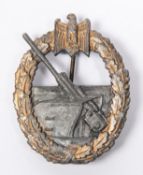 A Third Reich Coastal Artillery badge, with grey gun and gold wreath (worn), flat grey back and
