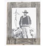 An autographed photograph of John Wayne, 10" x 8", in Western costume, signed vertically. In mount