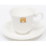 A Third Reich china cup and saucer with gilt eagle and swastika flanked by "AH", made by Allach,