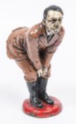 An unusual pin cushion caricature model of Adolf Hitler, bending over, made of metal, painted and