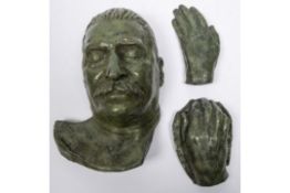 A bronze death mask of Stalin, 13" x 9"; also a similar pair of cast hand mouldings, patinated green