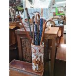 A ceramic stick stand containing a number of sticks and umbrellas.