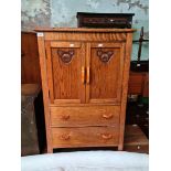 A 1930s oak tallboy with bakelite handles and carved panels to the doors.