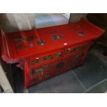 A Chinese red painted side cabinet decorated with eastern figures and flowers.