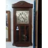 An early 20th century oak cased chiming wall clock with pendulum and key.