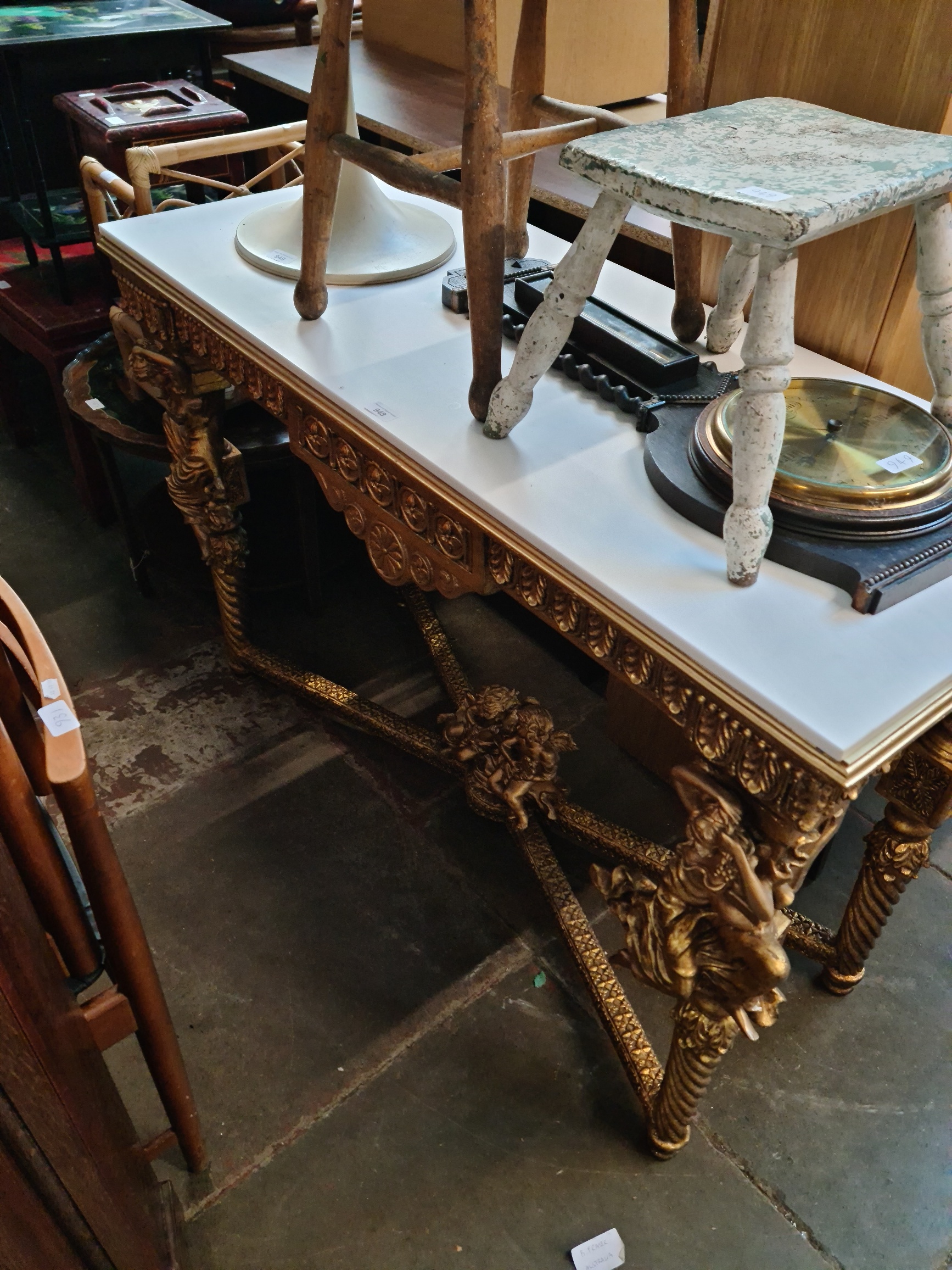 A gilt wood and composite top console table decorated with lady figures and cherubs.