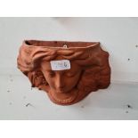 A terracotta wall sconce modelled as a woman.