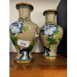 A pair of cloissonne vases decorated with flowers.