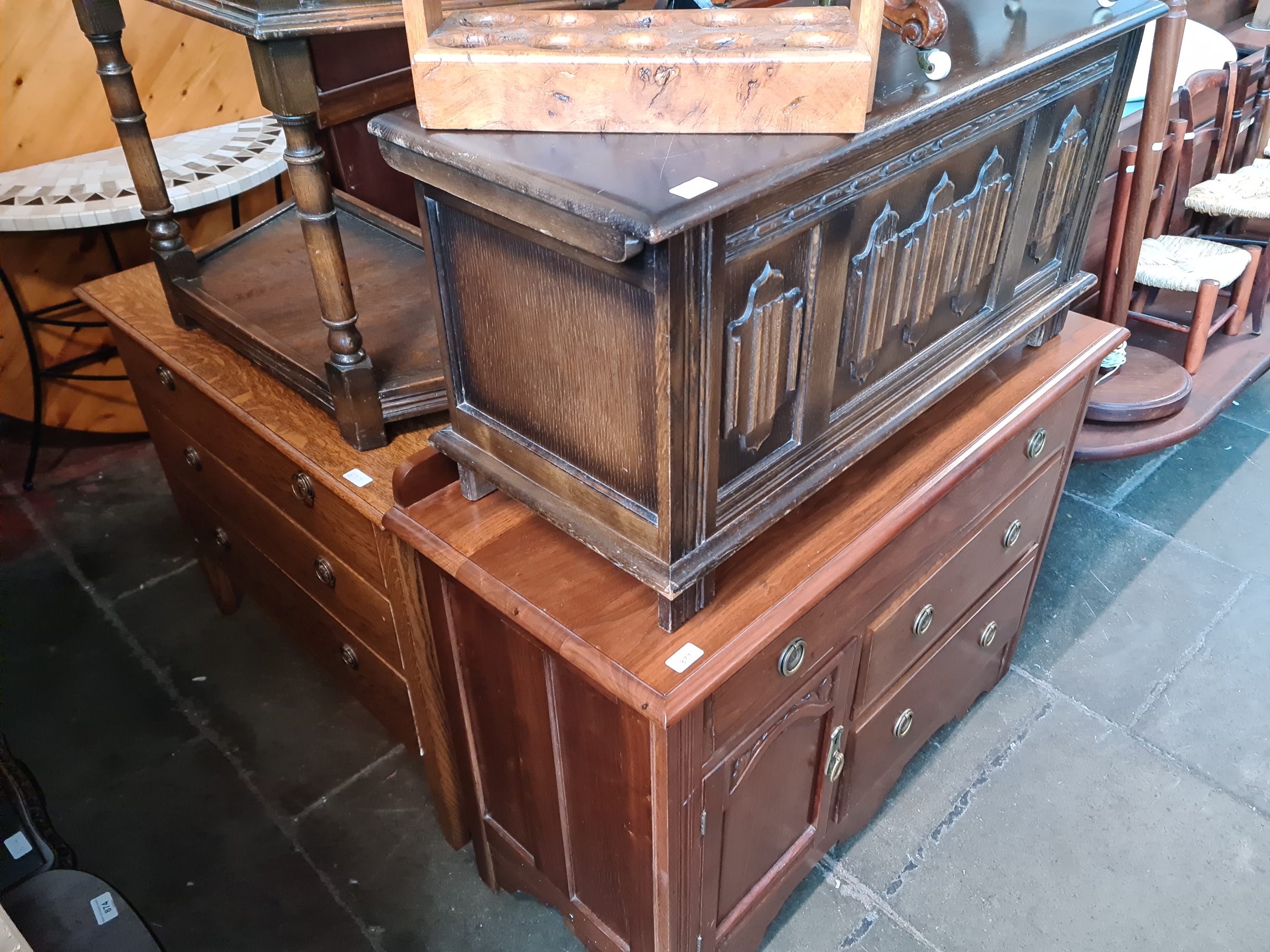 Three pieces of furniture comprising an oak chest of drawers, a walnut cabinet and a linen fold