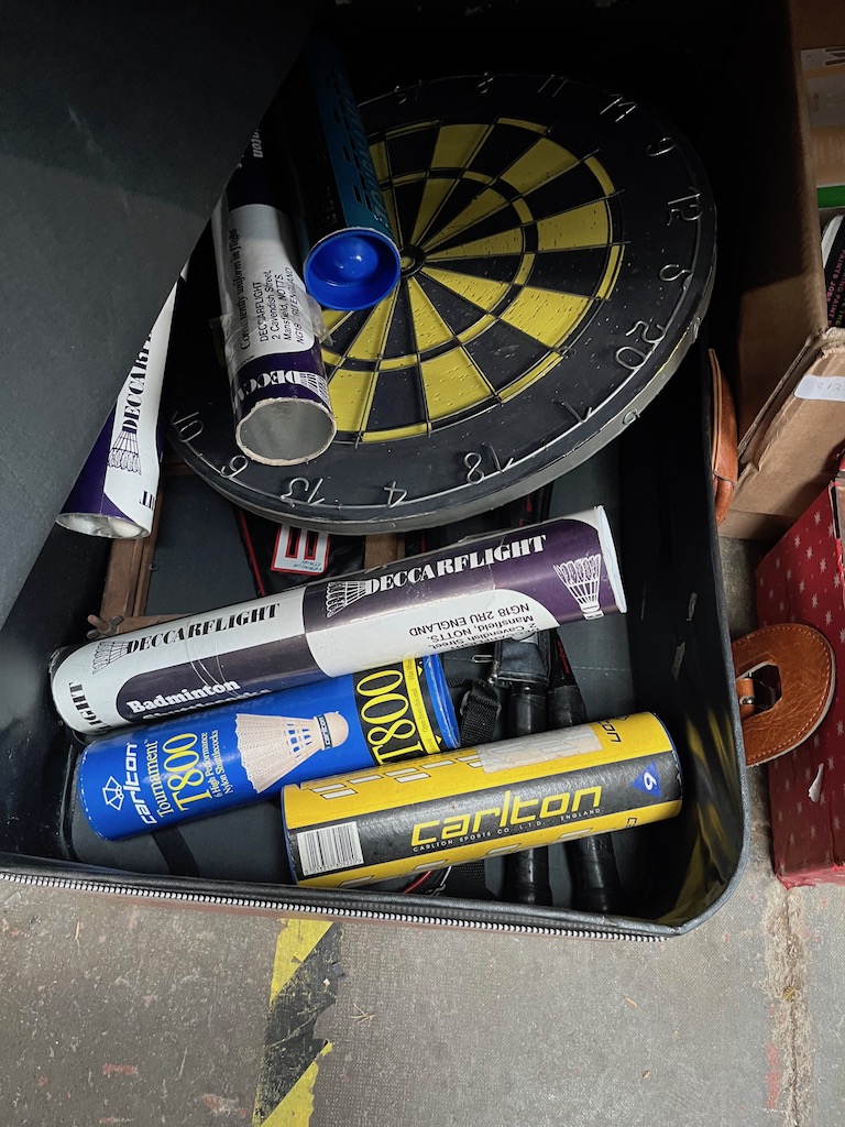 A box of sporting equipment including darts and boards, badminton racquets and shuttles etx