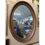 A vintage oval gilt framed mirror, 64cm x 89cm.