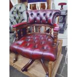 An oxblood red leather Chesterfield captain's chair.