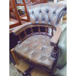 A brown leather Chesterfield captain's chair.