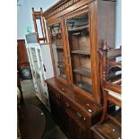 An Edwardian oak cabinet bookcase with carved panels to the doors, width 157cm, depth 50cm &