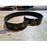 A military belt with assorted badges attached.