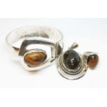 Three pieces of white metal jewellery set with quartz tiger's eye cabochons, comprising a bangle and