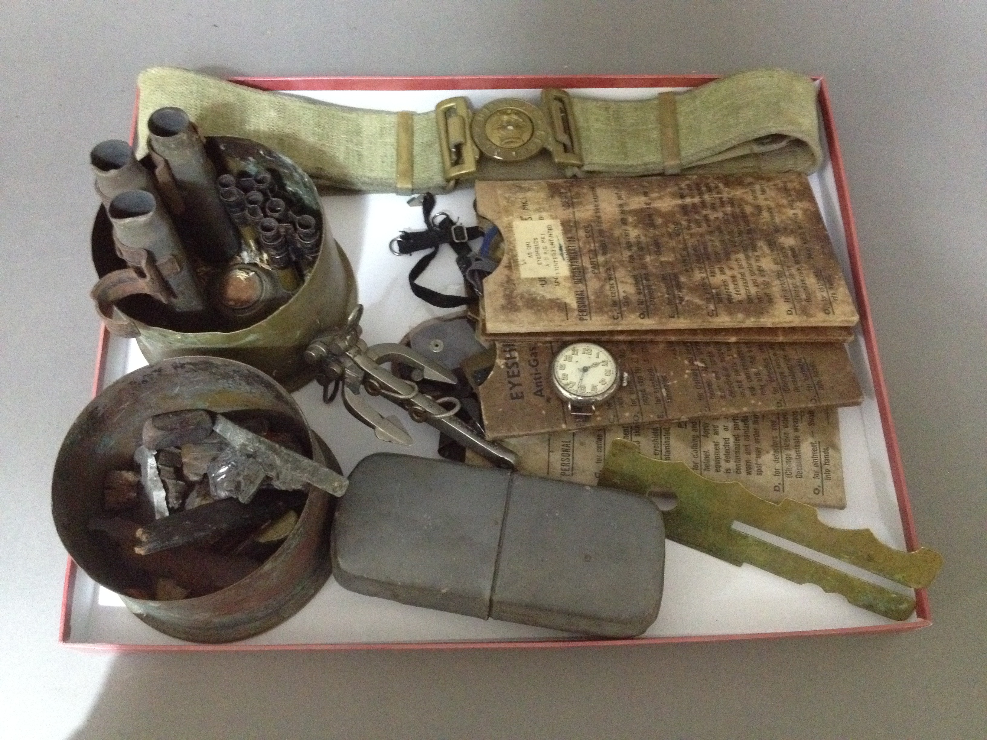 A selection of military items including a watch, 2 large shells cut in half, various metals,