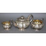 A George IV three piece silver tea set, compressed melon form, bright cut engraved with scrolls,