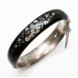 An Austrian/Hungarian black enamel and silver hinged mourning bangle, floral decoration set with