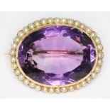 An antique amethyst and seed pearl brooch, the bezel set oval mixed cut amethyst weighing approx