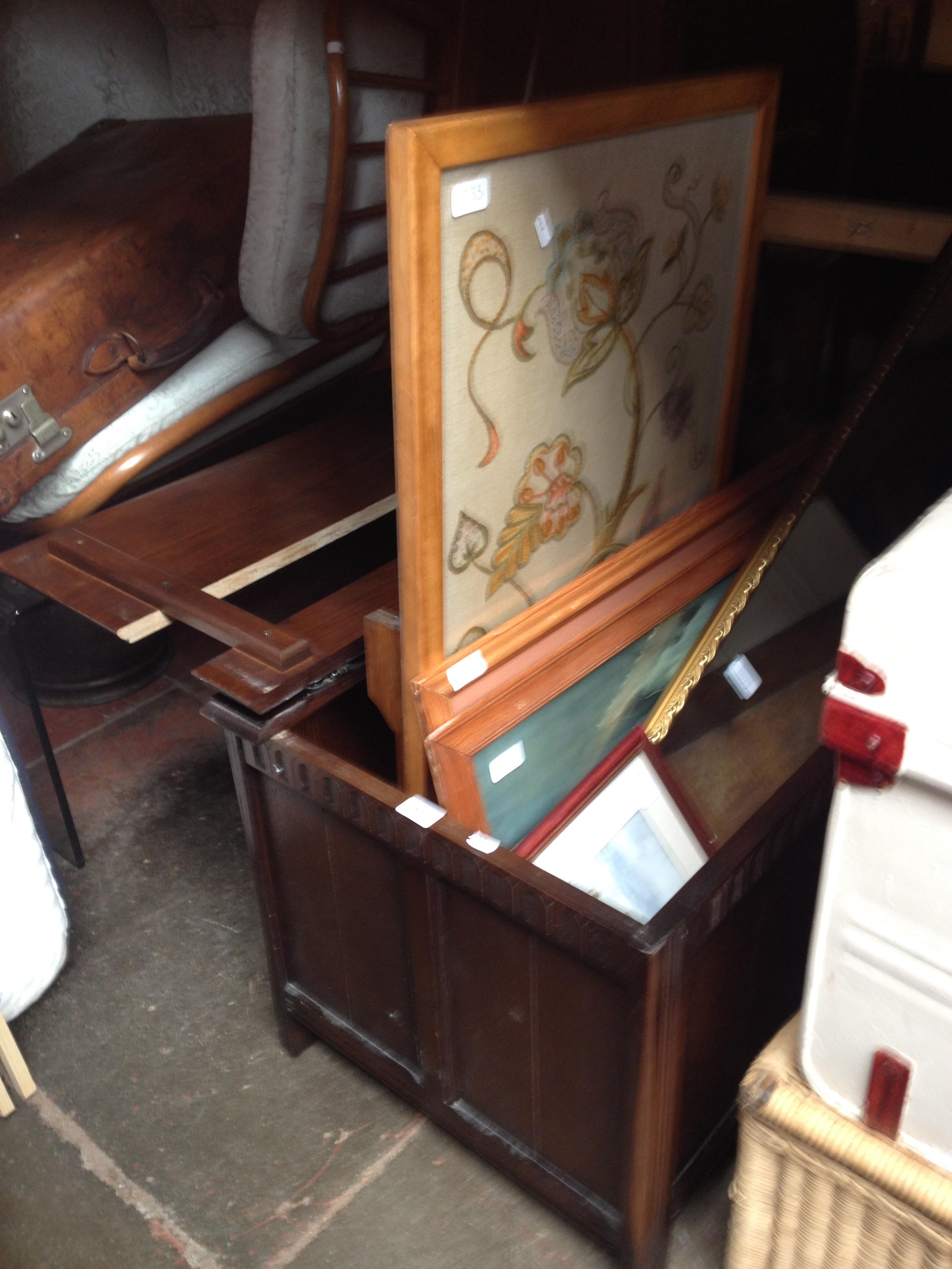 An oak bedding box containing various paintings, a mirror and a needlework firescreen/table.