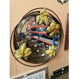 A metal framed mirror, the frame decorated with leaves and a flower, diameter 73cm (approx).