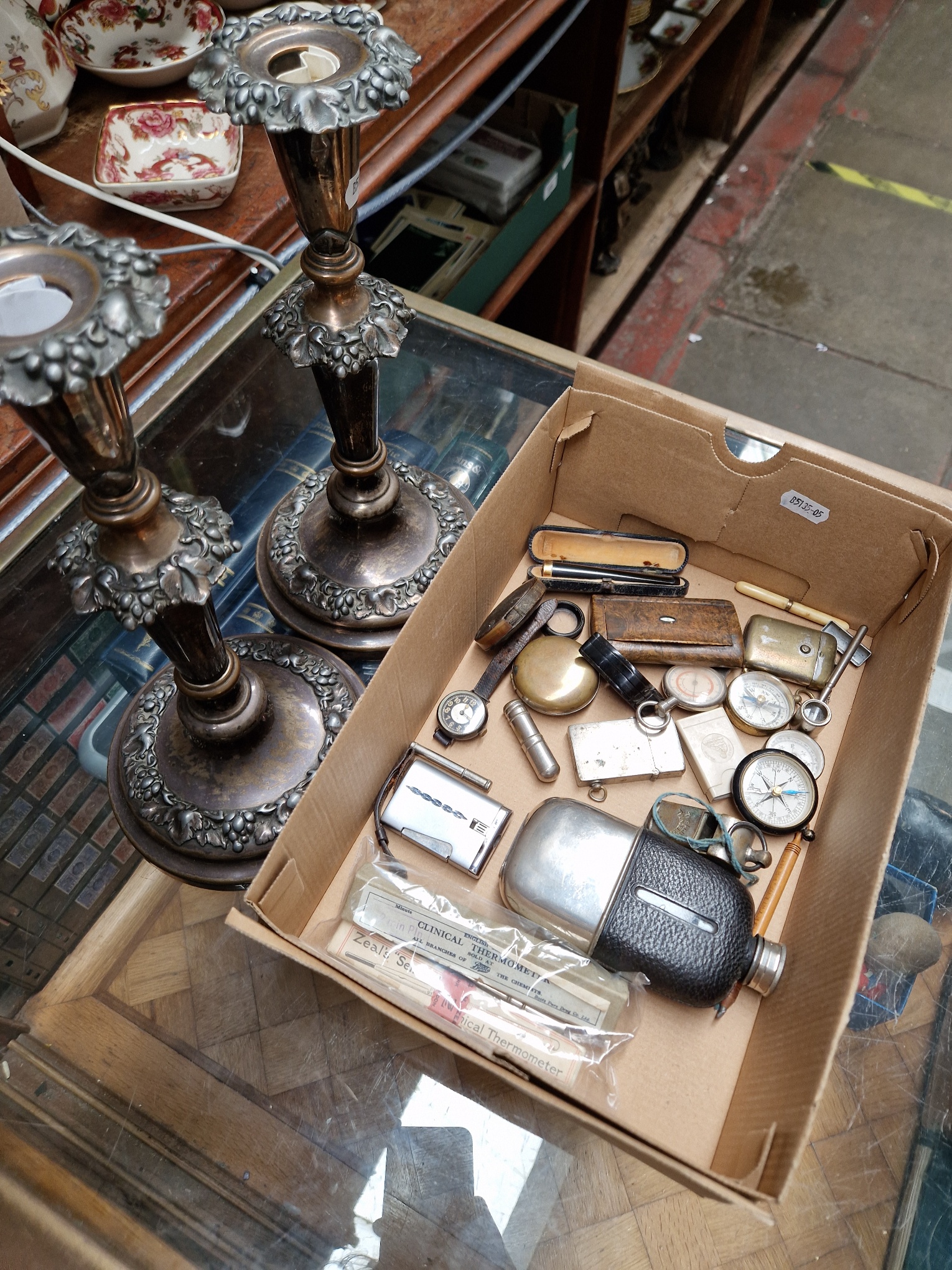 A box of mixed collectables including hip flask, compasses, silver cased wristwatch, lighters, snuff