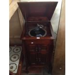 A 1920s inlaid mahogany cabinet gramophone with a number of records.