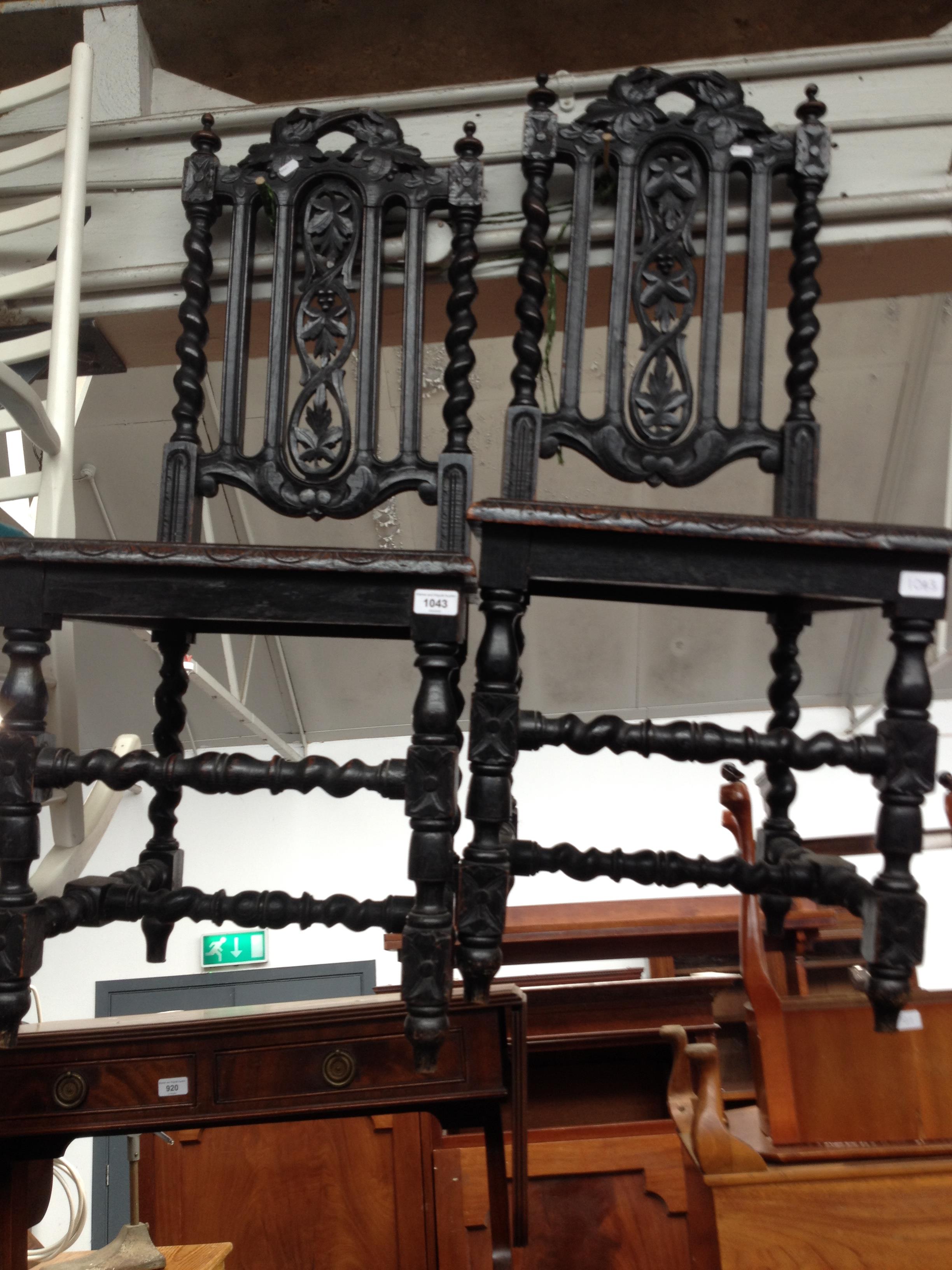 A pair of 19th century ebonised carved oak chairs.