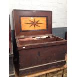 An antique joiner's toolbox with marquetry inlay to the interior containing a number of vintage