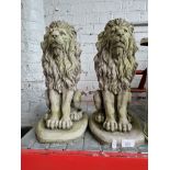 A pair of concrete garden ornaments in the form of lions