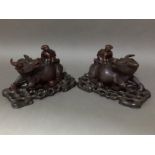 A pair of Chinese carved hardwood water bufflao with riders and wood stands, length 31cm each.