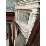 A large Victorian white painted fire surround with mirror to top and architectural column supports.