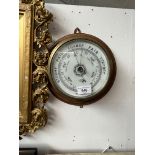 A brass aneroid barometer signed Gamage London, mounted on oak.