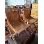 A pair of late Victorian Gothic Revival x-frame oak hall chairs.